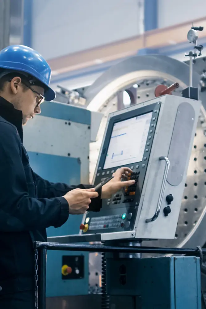 Ein Mann drückt Schalter an einer automatisierten Maschine